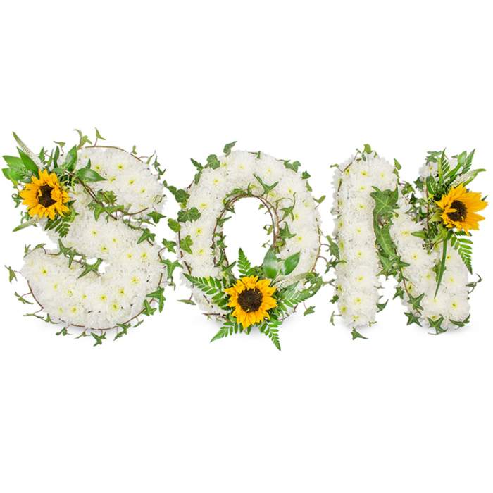 A sculpted floral tribute forms the word SON in three emphatic capital letters, each letter completely cloaked in tiny, pristine white chrysanthemums that create a thick, soft tapestry of petals. Winding through the white surface are strands of dark green ivy and delicate fern fronds, the ivy's pointed lobed leaves and the fern's feathery blades breaking the white plane and lending organic movement to the composition. Three vivid sunflowers provide deliberate points of colour and emotion: a large sunflower sits on the S's upper-left curve, another is nested at the O's lower centre amid the green fronds, and a third is set on the N's upper-right corner. The sunflowers' golden-yellow rays radiate around their textured, dark brown centres, producing a contrast that brings light into the otherwise calm palette. Set against a plain white background, the arrangement's contours and shadows are crisp, revealing the florist's meticulous placement of each chrysanthemum and the gentle intertwining of ivy stems. Visually, the piece balances purity and vitality - the white blooms speaking of peace and the sunflowers suggesting warmth and memory. The overall scent is imagined as faintly green and floral rather than heady, suitable for a reverent space like a funeral chapel or a family gathering in a nearby Primrose Hill home. As an experienced local florist, I picture this arrangement on a memorial table overlooking the park or carried into a small service on Regent's Park Road, offering a tangible expression of love and remembrance for a son.