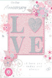 This anniversary card offers a gentle, romantic scene, blending pastel pinks, soft whites, and silvery greys into a composition that feels as intimate as an evening stroll around Primrose Hill's leafy streets. At the centre of the design, the word LOVE appears in raised lettering, its surface dusted with a fine glitter that gives the impression of starlight resting on the paper. The letter O is subtly suggested as a heart-shaped curve within the design, echoing the rounded softness of a classic romantic motif. The central word sits on a blush-pink ground that glows faintly, creating a warm focal point. Around it, a cloud of delicate flowers and trailing vines spreads across the card face, rendered in the soft, flowing lines of a watercolour sketch. The blooms are tinted in blush and mauve tones, with a few petals highlighted in silver, reminiscent of the understated elegance of floral arrangements seen in the independent shops near Gloucester Avenue. Tiny flourishes-scattered petals, swirling lines, and almost-secret butterflies-add movement, as if the design were gently stirred by a light spring breeze. In an elegant, script-style font, the phrases On Our Anniversary and I love you today and always are written with understated grace, their curves echoing the natural arcs of the floral stems. There is a sense of cherished history in the composition, as though every line and petal honours shared memories. The whole card feels like a paper bouquet, softly glowing and deeply heartfelt, perfect for marking a quiet yet meaningful anniversary in the Primrose Hill area.